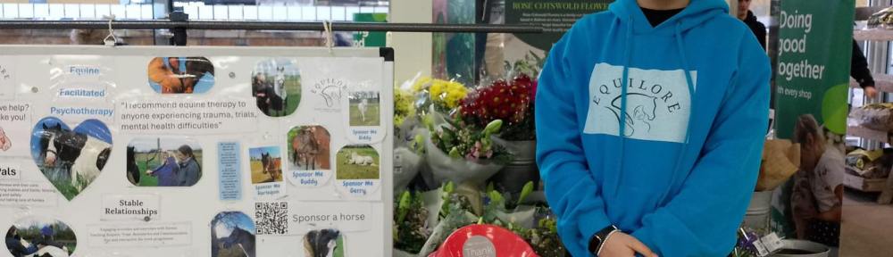 Supporter Amira pictured next to a stall with information about Equilore.