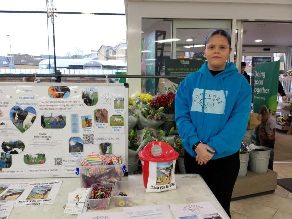 Supporter Amira pictured next to a stall with information about Equilore.